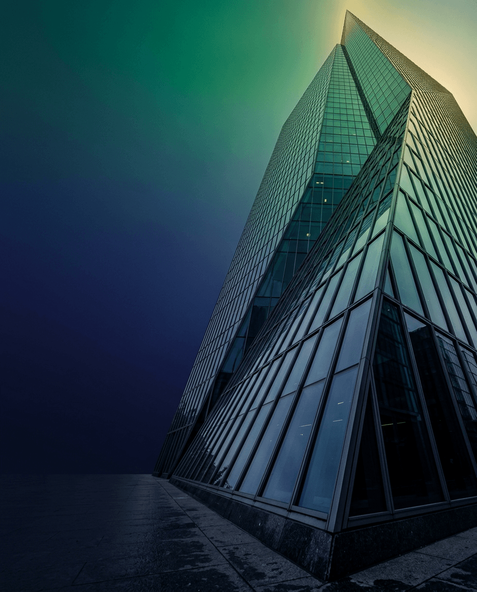 A glass-fronted corporate tower viewed from street level at dusk